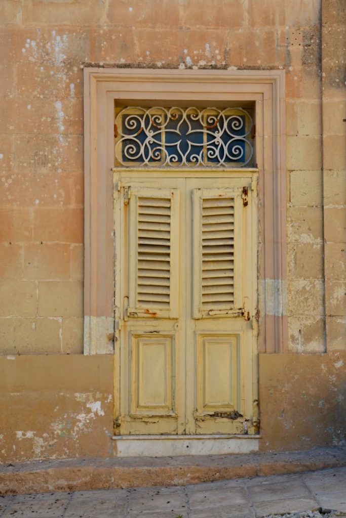 Old weathered yellow door on a Mediterranean building in Malta, showcasing vintage charm.
